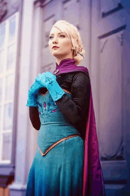a woman in a blue dress and purple cape