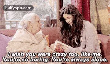 a woman is sitting next to an elderly woman on a couch and talking to her .
