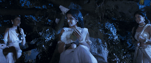 a woman in a white dress is sitting in a tree