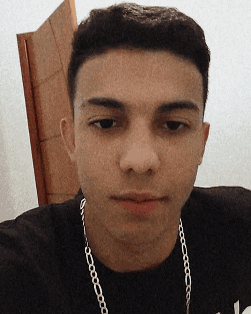 a man wearing a chain around his neck looks at the camera