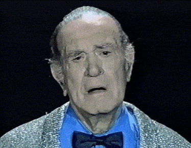 an older man wearing a blue shirt and a bow tie is making a sad face