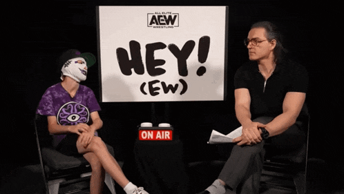 two people are sitting in front of a sign that says hey ( ew )