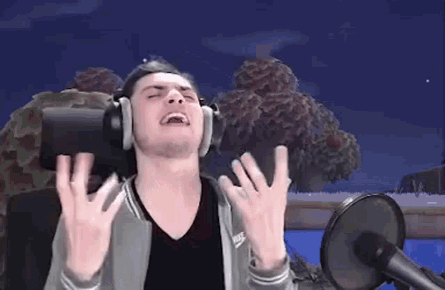 a man wearing headphones is making a funny face while sitting in front of a microphone .