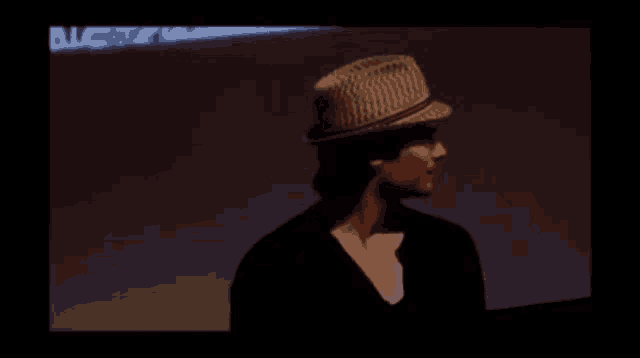 a man wearing a hat is standing in front of a blue wall