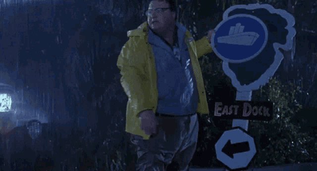 a man in a yellow raincoat is standing in front of a sign that says east dock