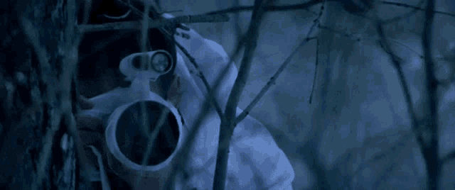 a man in a white shirt is looking through a telescope in the woods