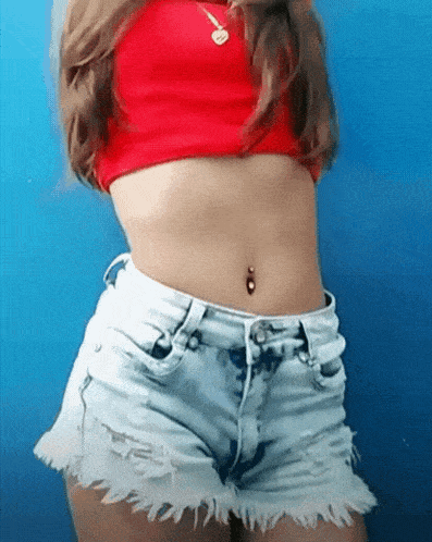 a woman in a red crop top and white shorts