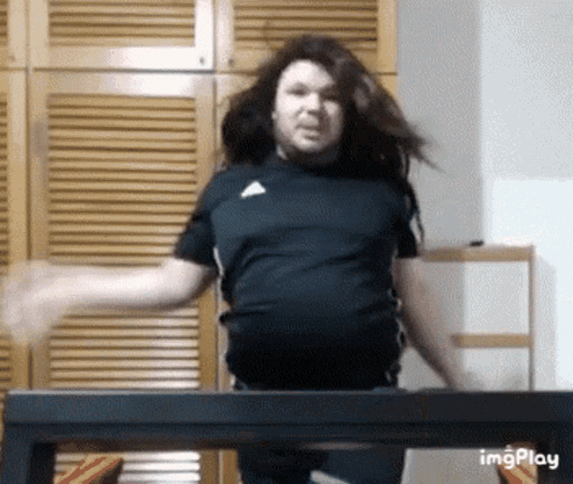 a man in a black shirt is standing in front of a table with his arms outstretched .