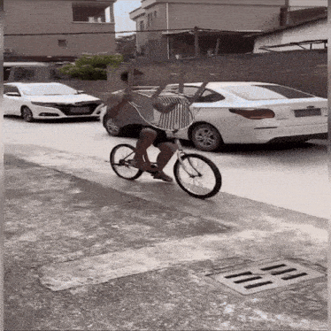 a man is riding a bike on a street with cars parked in the background