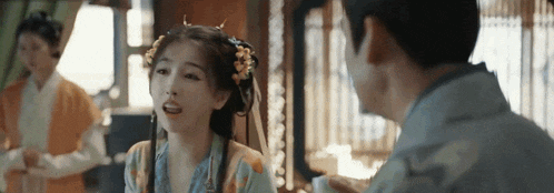 a woman in a traditional costume is talking to a man in a kimono .