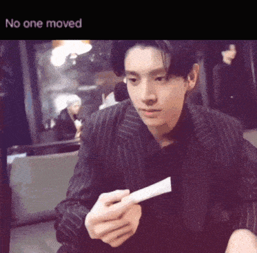 a man in a suit is holding a piece of paper with the words " no one moved " underneath him