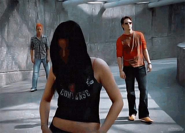 a woman wearing a black converse tank top stands in a hallway
