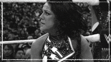 a black and white photo of a woman in a wrestling ring with a crowd behind her