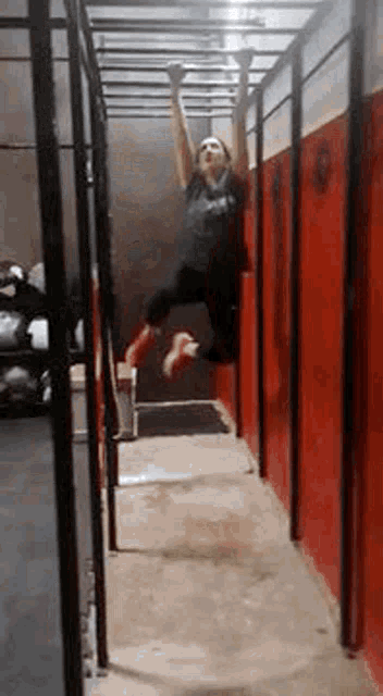 a woman is hanging from a bar in a gym