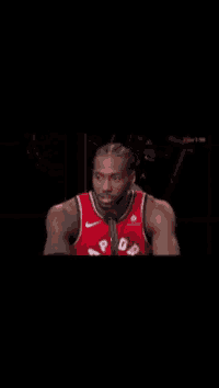 a basketball player wearing a red raptors jersey is smiling