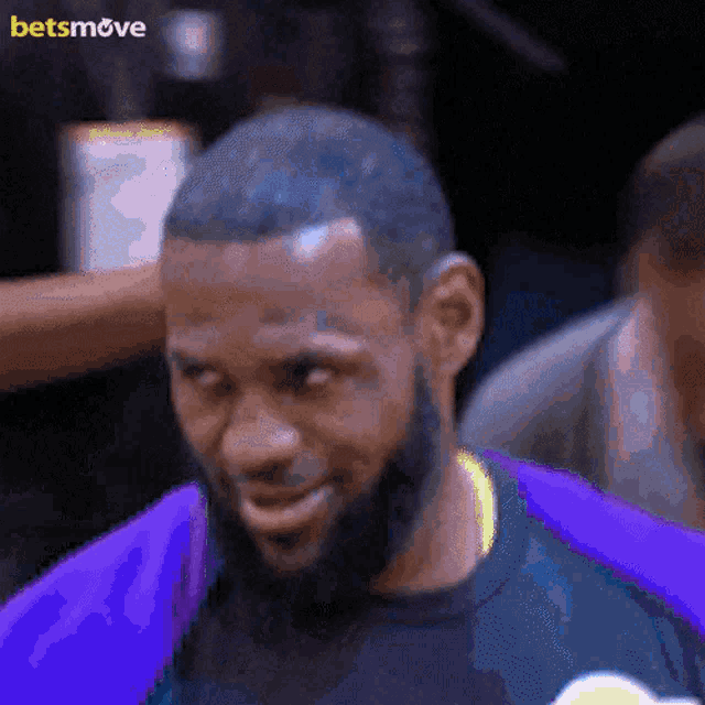 a man with a beard wearing a purple shirt with a betsmove logo on the bottom