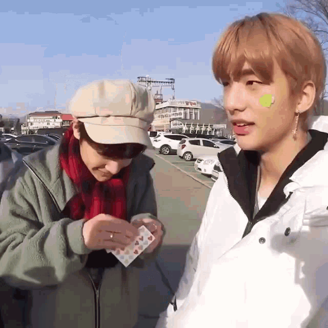 a man with a green sticker on his face is holding a card with hearts on it .