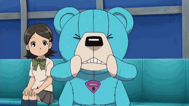 a girl sits next to a teddy bear with a superman emblem on it