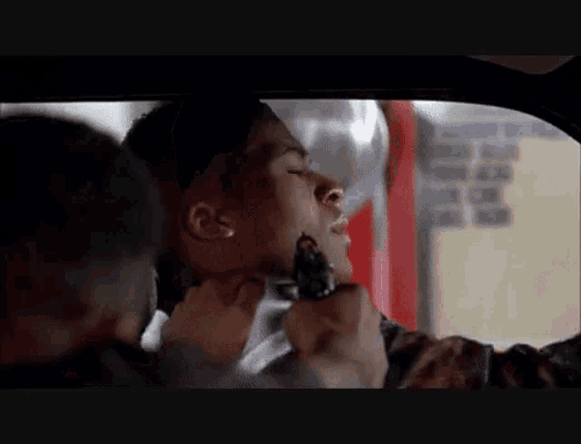 a man in a car is being held by another man with a gun