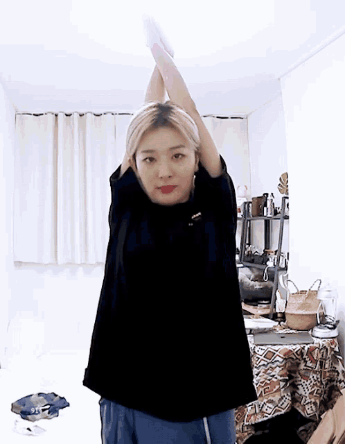 a woman in a black shirt is stretching her arms