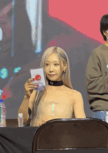 a woman sitting in a chair holding a card that says gf on it