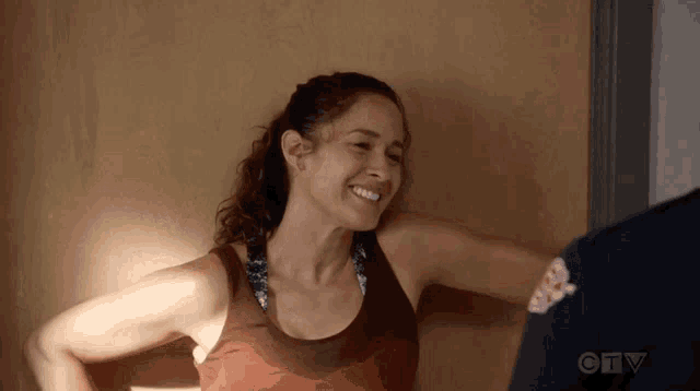 a woman in a tank top is smiling while standing next to a man in a uniform .