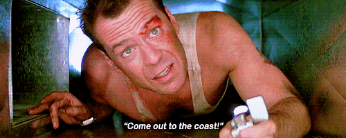 a man in a white tank top is holding a lighter and says " come out to the coast "