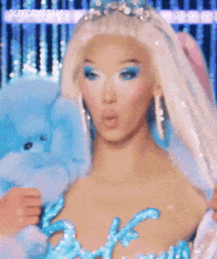 a woman in a white wig and blue earrings is wearing a blue dress .