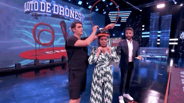 two men and a woman on a stage with a sign that says ' loto de drones ' on it