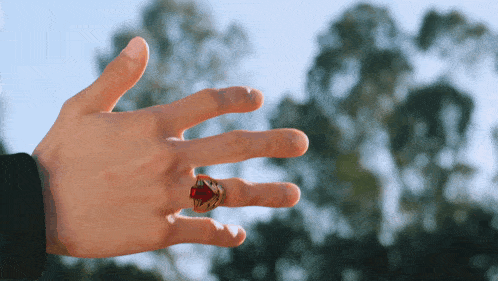 a man 's hand with a red ring on his finger