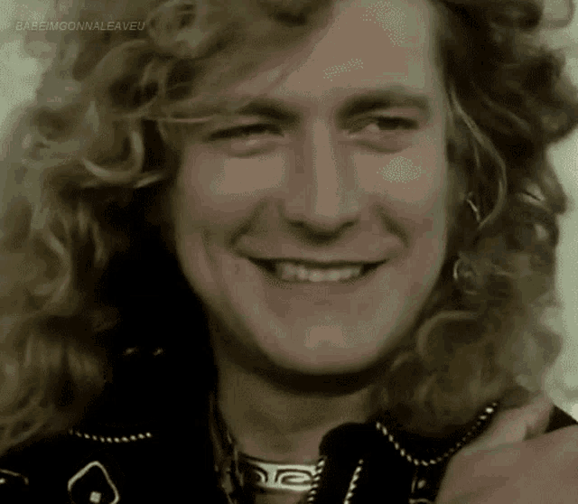 a close up of a man 's face with curly hair smiling