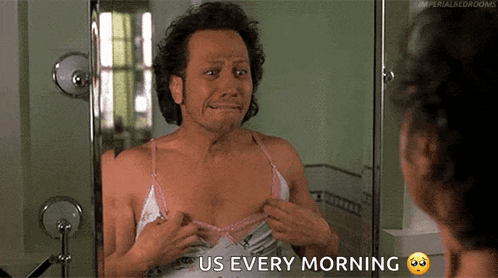 a man in a pink bra is looking at himself in the mirror with the words us every morning above him