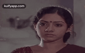 a woman with a bindi on her forehead is looking at the camera .