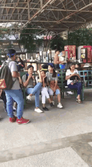 a coca cola vending machine is in the background of a group of people