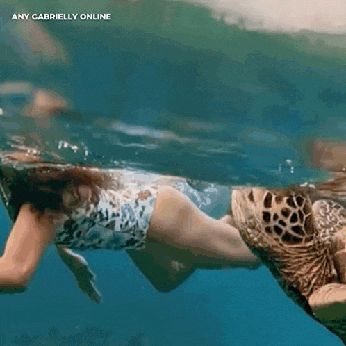 a woman is swimming with a sea turtle and the words any gabrielly online are on the bottom
