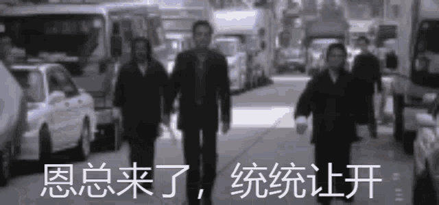 a group of men walking down a busy street with chinese writing on the bottom