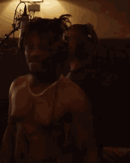 a man without a shirt is wearing headphones and a necklace