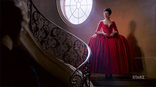 a woman in a red dress is standing on a set of stairs with the word starz on the bottom