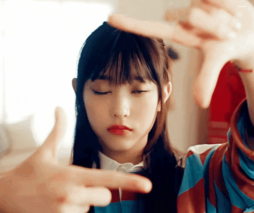a young girl with her eyes closed is making a finger frame with her hands