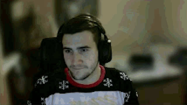 a man wearing headphones and a sweater is sitting in a chair .