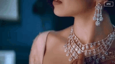 a close up of a woman 's neck wearing a diamond necklace and earrings .