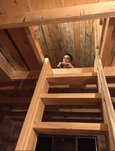 a man is looking up from a wooden staircase