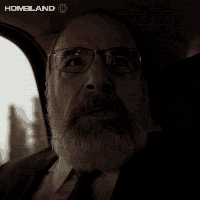 a man with glasses and a beard is sitting in a car with the words jesus christ written below him