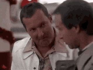 two men are talking to each other in a restaurant and one of them is holding a gun .