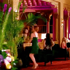 a woman in a green dress is dancing in a room with other people