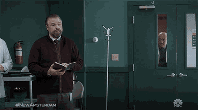a man standing in front of a green door with the hashtag #newamsterdam on the bottom