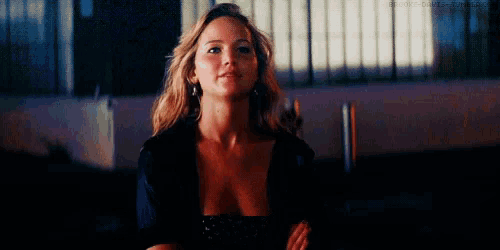 a woman in a black top is looking at the camera with her arms crossed .