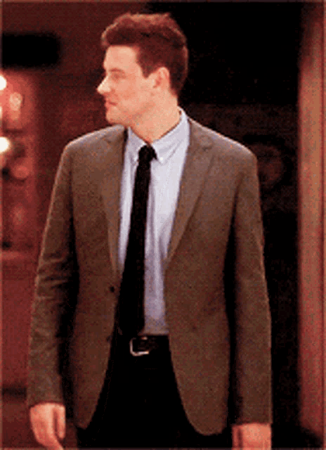 a man in a suit and tie is standing in front of a door
