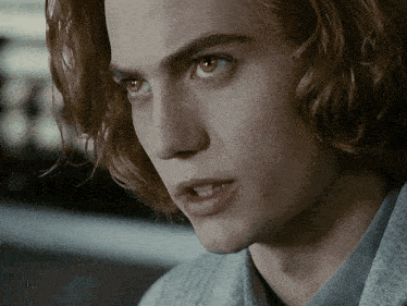 a close up of a man 's face with a gray sweater on
