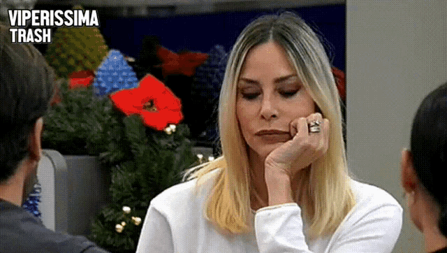 a woman with a ring on her finger is sitting in front of a christmas tree with the words viperissima trash written above her